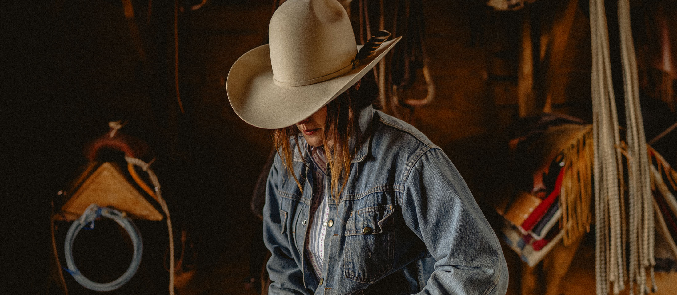 A woman wearing looking down while wearing a cowboy hat.